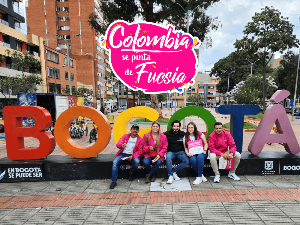 A group of people sitting on a bench in front of a sign.